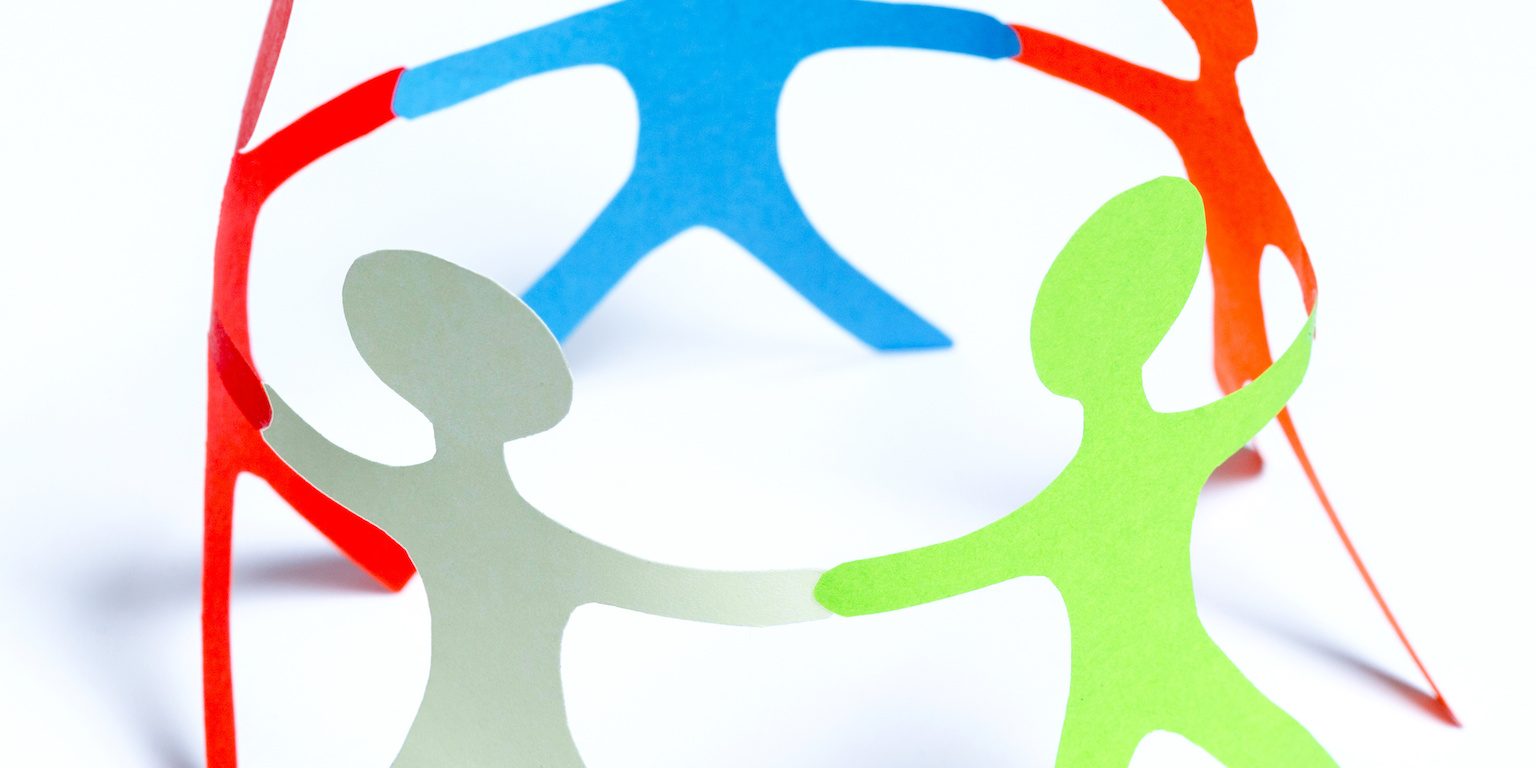 Paper people of different colors standing in a cycle holding hands